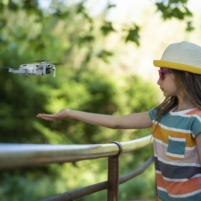 Little girl holds out her hand for a small drone to land on it